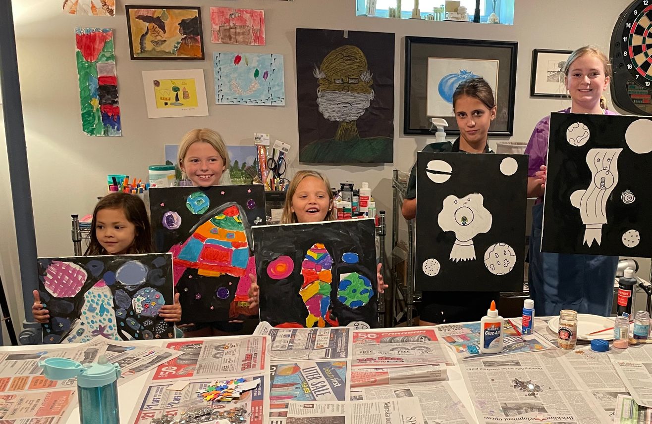 A group of kids holding up their paintings